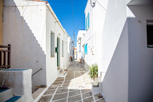 Typical urban with whitewashed houses empty clean cobblestone narrow alley sunny day at Kythnos island, Chora village Cyclades summer destination Greece.