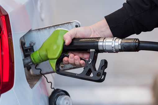 Close up of a woman filling up gas in her car at the gas station. Transportation, Environment, fuels.