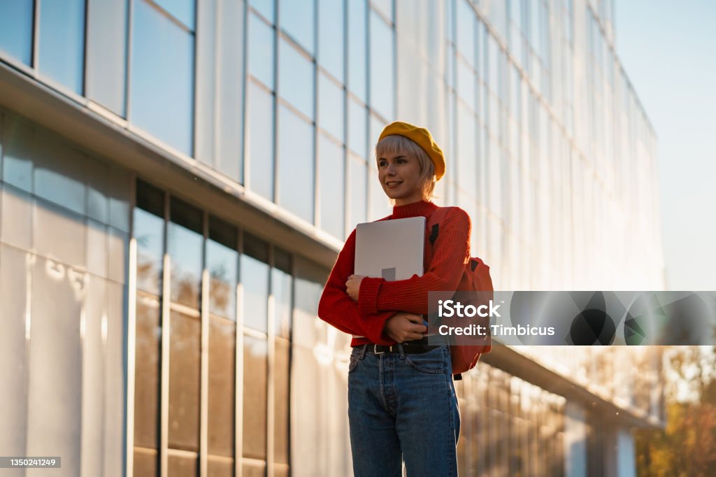 STEM female University student int he campus Portrait of a modern young female student in front of a University building holding a laptop Candid Stock Photo
