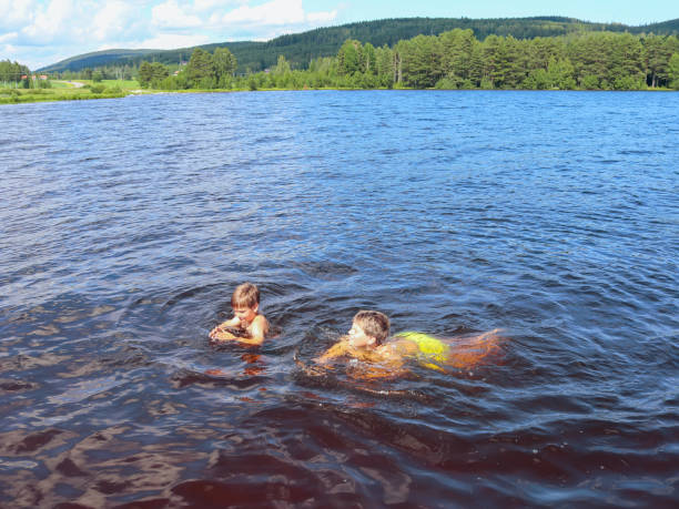 istock Two boys are learning to swim in the lake 1350244674
