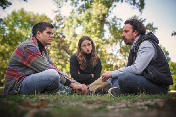 istock Three friends sit together in park and talk about problems 1350248822
