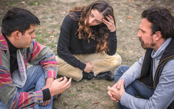 istock Three friends sit together in park and talk about problems 1350249380