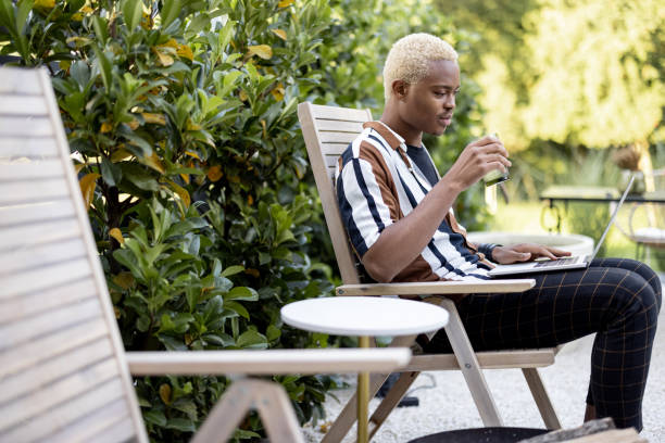 istock Latin man using laptop on lounger at house garden 1350249628
