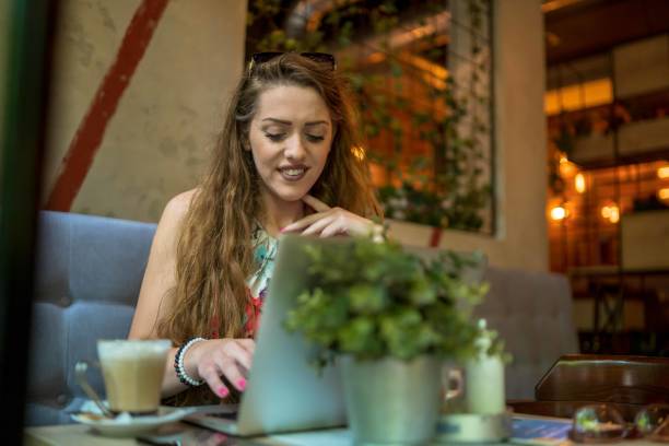 istock Businesswoman using laptop while enjoying work at cafe table with cup of coffee 1350251457