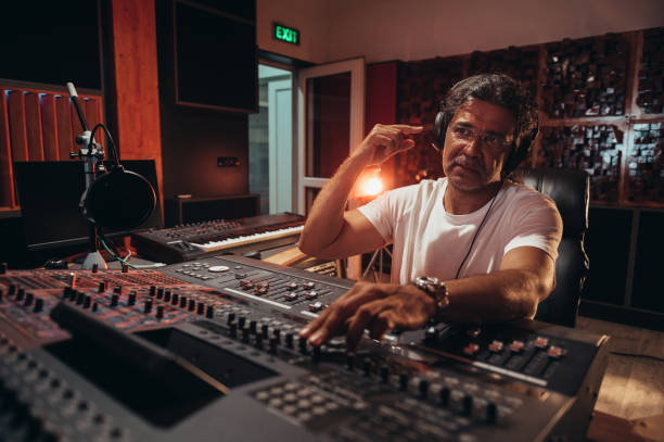 istock Senior hispanic music producer working on a mixing soundboard while in his studio 1350251529
