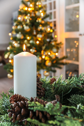 Beautiful candle with Christmas decor on white background