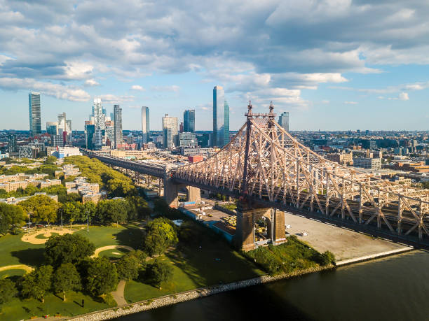 Aerial of Queensboro bridge on a cloudy day Aerial of Queensboro bridge New York with a view of East river and Roosevelt island new york city built structure building exterior aerial view stock pictures, royalty-free photos & images