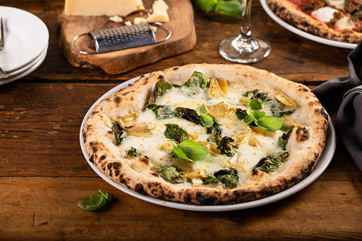 Pizza bianca or white pizza with cheese, artichokes and fresh basil