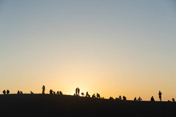 Gelemis, Turkey - July 7, 2021: Silhouettes of local people and tourists who gather at sunset in the summer on the dunes of Patara Plaji beach on the Mediterranean coast to watch the sun go down and socialize