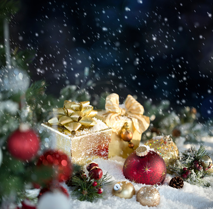 Christmas Red and Gold Baubles with Gifts on a Snowy Blue Background with Bokeh. Very shallow depth.