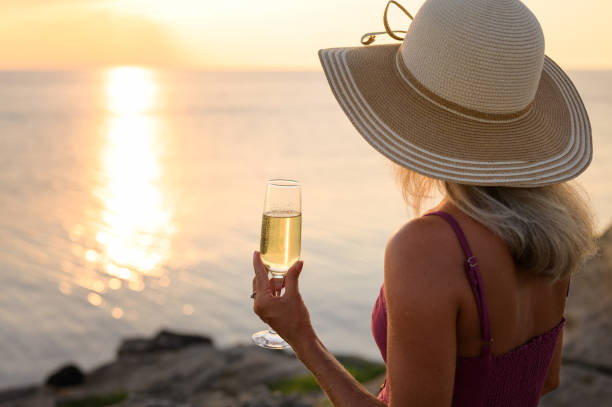 夕方の女の子は、シャンパンのグラスと高い丘の上に海のそばに座っています。 - sunrise hill sea sun ストックフォトと画像