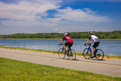 Sandwich, Massachusetts, USA- June 8, 2021- Two men ride their bicycles along the paved and well maintained two lane bicycle path that runs for seven miles along both sides of the Cape Cod canal.  This bikeway is popular with walkers, joggers, in line skaters and others just enjoying watching the boat traffic on the Canal.