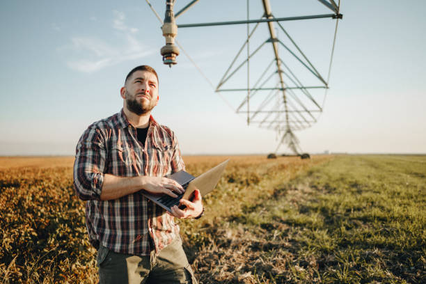 Young farmer standing in wheat field and setup irrigation system