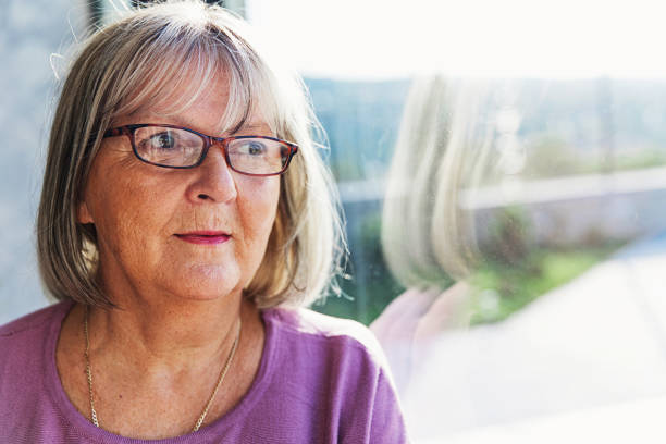 Pensive Mature Woman Looking Out of the Window Mature woman looking out of the window 60 69 years stock pictures, royalty-free photos & images