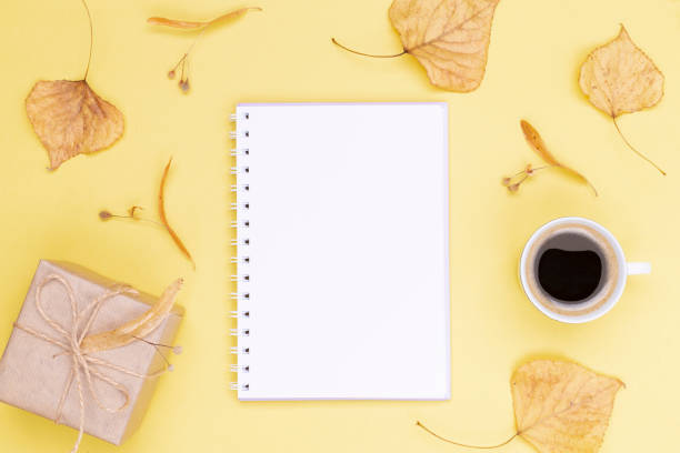 istock Autumn composition. Clean diary with a spring, gift wrapped in kraft paper, autumn leaves, a cup of coffee against a yellow background. Flat lay, top view, copy space 1350291883