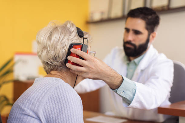 Hearing test and buying hearing aid Senior woman doing hearing test at specialized medical clinic for hearing disabilities. Doctor putting headphones on her head and she is pressing button when she her a sound ear exam stock pictures, royalty-free photos & images