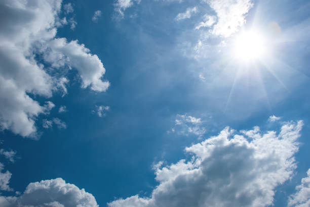 istock Air white clouds, sun with long rays and glare in the blue sky. Sky landscape 1350315218