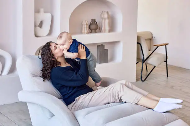 Photo of Woman spends time with infant on sofa in living room.