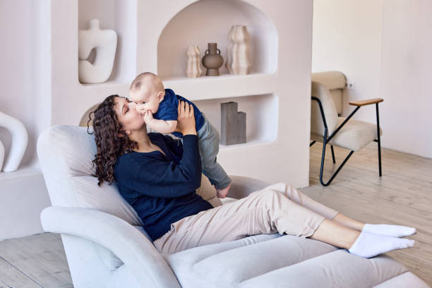 woman spends time with infant on sofa in living room. - sunbed imagens e fotografias de stock