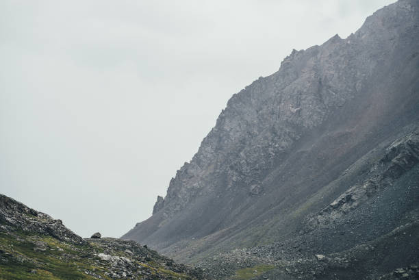 istock Atmospheric highlands landscape with narrow mountain valley and sharp rocks on steep slope under gray sky. Bleak mountain scenery with pointed rockies on mountainside and glen in overcast weather. 1350320169