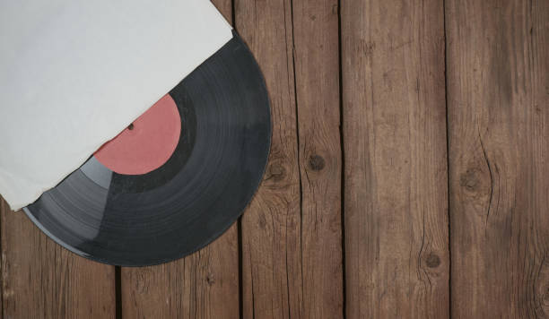 istock Old vinyl record in paper case on wooden rustic background. 1350320697