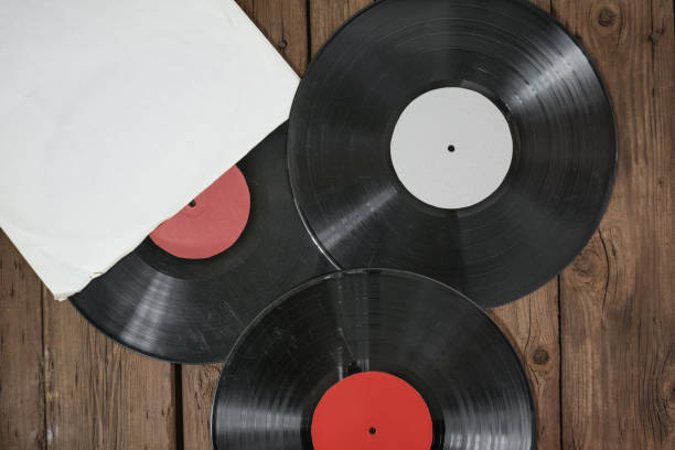 istock Three old vinyl records in paper case on wooden rustic background. 1350320701