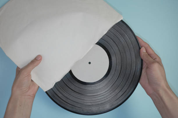 istock Hands hold an old vinyl record in an old paper case on a light blue background. 1350320703