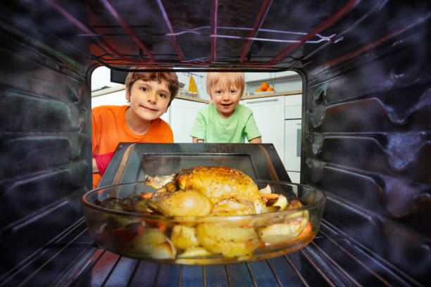 Two little boys open the oven door to take fried chicken dish view from inside