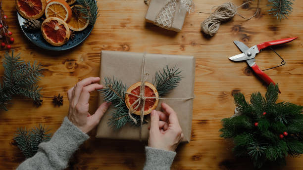 女性の手はクリスマスプレゼントを飾る - christmas paper wrapping paper paper gift ストックフォトと画像