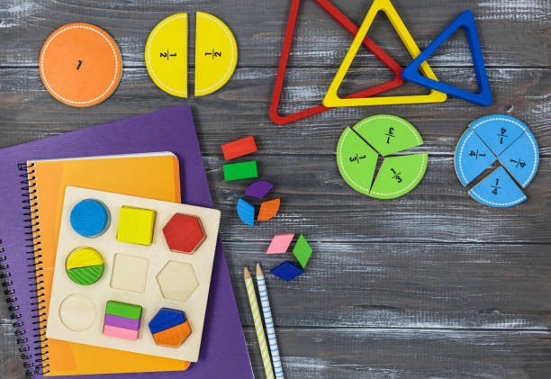 istock Multicolored fractions, blocks, notebook on a gray wooden table. Back to school, fun math, games for kindergarten, preschool education. 1350328743