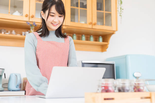 istock young asian woman using laptop,kitchen 1350336460