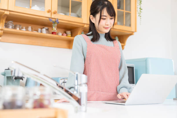 istock young asian woman using laptop,kitchen 1350336526