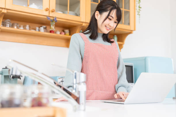 istock young asian woman using laptop,kitchen 1350336555