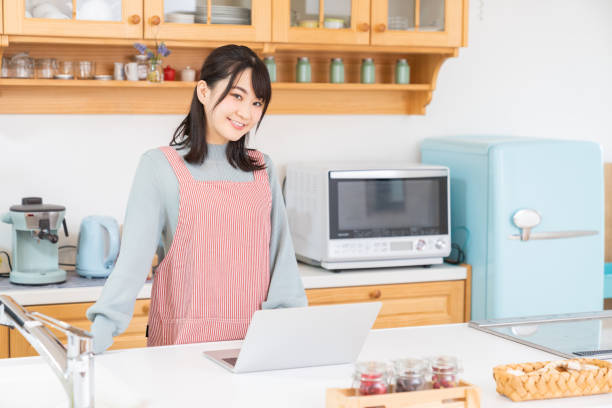 istock young asian woman using laptop,kitchen 1350336585