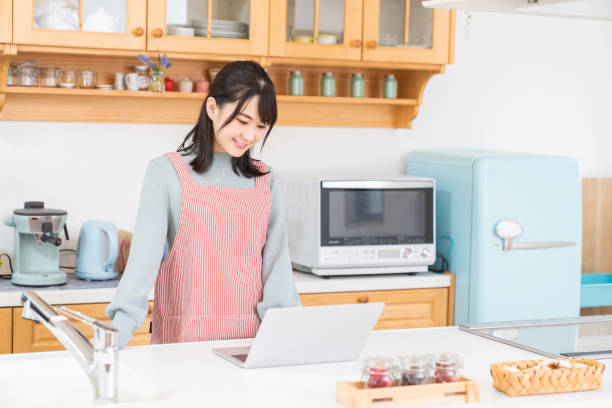 istock young asian woman using laptop,kitchen 1350336631