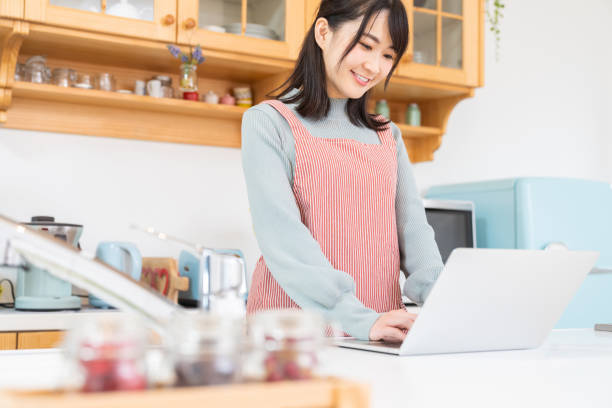istock young asian woman using laptop,kitchen 1350336694