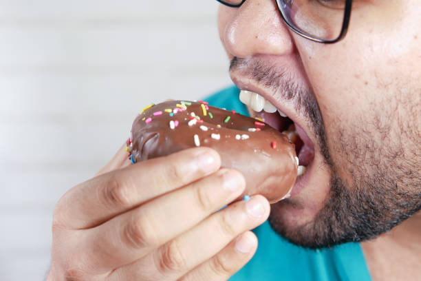 istock close up of young man eating donut , 1350338931