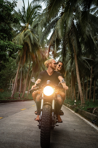 Young couple enjoying the motorbike ride on the tropic country road.