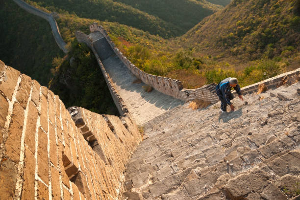 Chinese man climbs up steep steps at the Great Wall of China stock photo