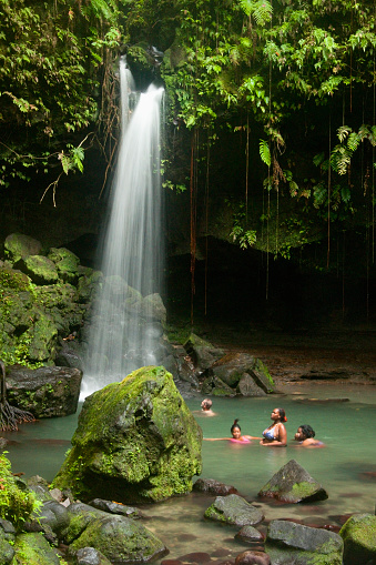 Morne Trois Piton National Park, Dominica - July 11, 2011: A group of locals and tourists swim under the 40-foot waterfall at Emerald Pool, a UNESCO site, West French Indies, Caribbean, Central America