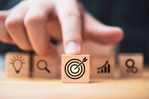 hand  touching and push target board which printing on wooden cube block on mechanical gear and lightbulb icon  for creative and set up business objective target  goal concept. - aspirations imagens e fotografias de stock