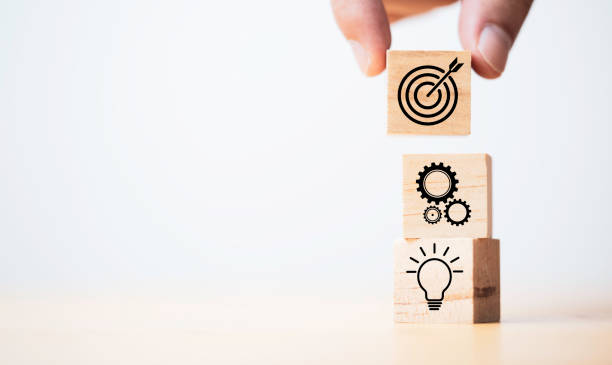 istock Hand putting target board which printing on wooden cube block on mechanical gear and lightbulb icon  for creative and set up business objective target  goal concept. 1350349376