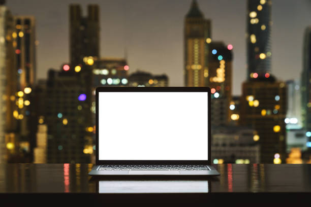 istock laptop computer on workspace white blank screen display city on night background 1350361843
