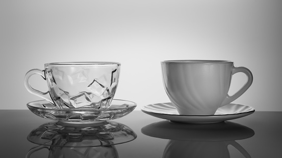 glass and porcelain empty cups on a saucer on a dark table with a reflection