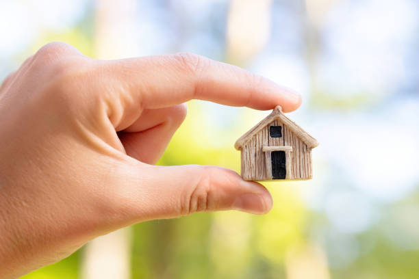 House figurine in hand outdoors Close-up of a house figurine in hand. Residential property insurance concept. tiny house stock pictures, royalty-free photos & images