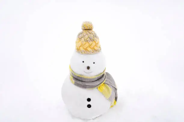 Photo of Snowmen wearing winter hat, scarf on white isolated background in trendy yellow and grey colors. 2021.