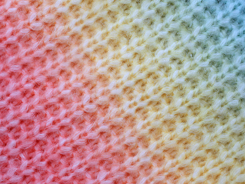 knitted cotton structure with a gradient from red to yellow to blue, close up of knitted cotton surface