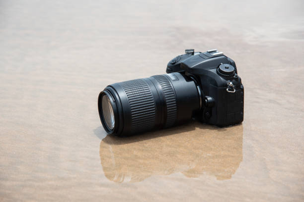 istock DSLR camera on beach wet from water sea wave 1350368973