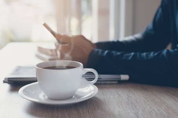 istock Cup of black coffee and  man using smartphone 1350379327