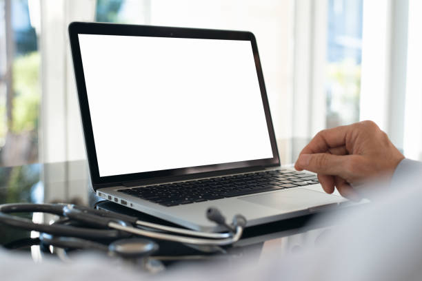 Doctor using laptop Mockup image, doctor working on blank screen laptop computer in modern doctor office with stethoscope and notebook on desk physician computer stock pictures, royalty-free photos & images